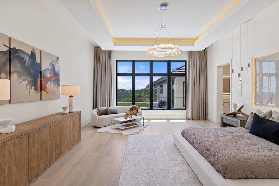 A spacious primary bedroom features tray ceilings and abundant natural light from expansive windows.