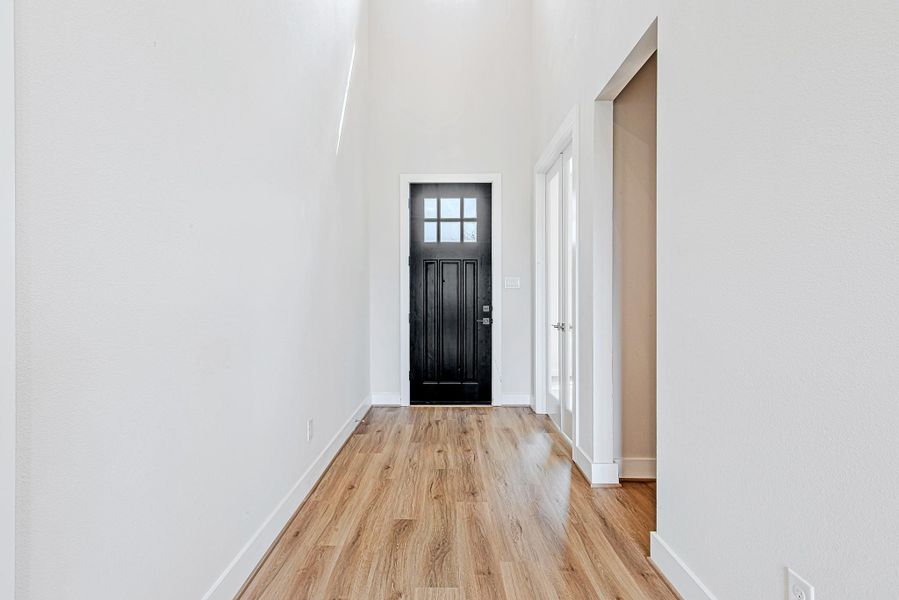 This alternate perspective of the foyer highlights the sleek black front door, flanked by double glass-paned French doors—ideal for a home office or study. The clean, neutral palette offers a bright and airy first impression.