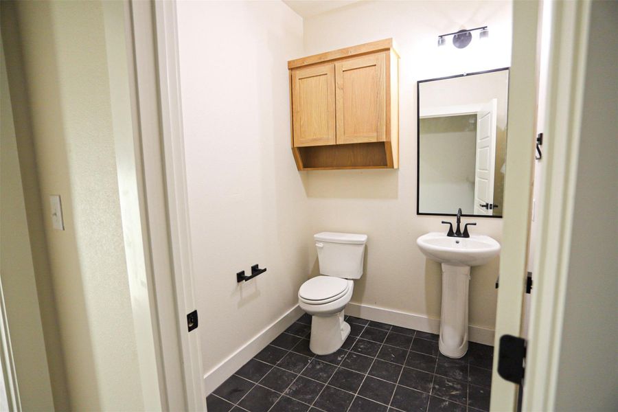 Half bath featuring toilet and dark tile patterned flooring