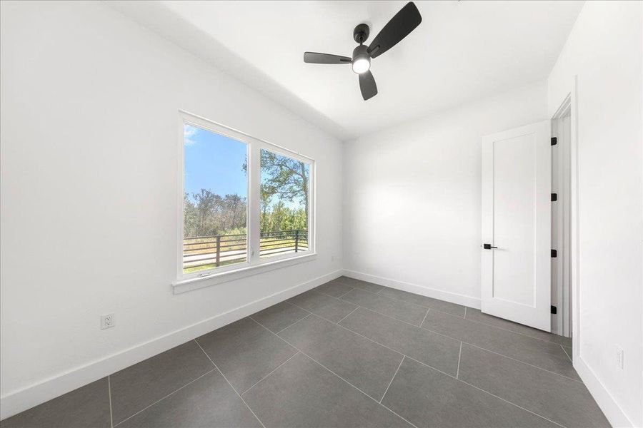 Unfurnished room featuring ceiling fan and dark tile patterned floors Unfurnished room featuring ceiling fan and dark tile patterned floors