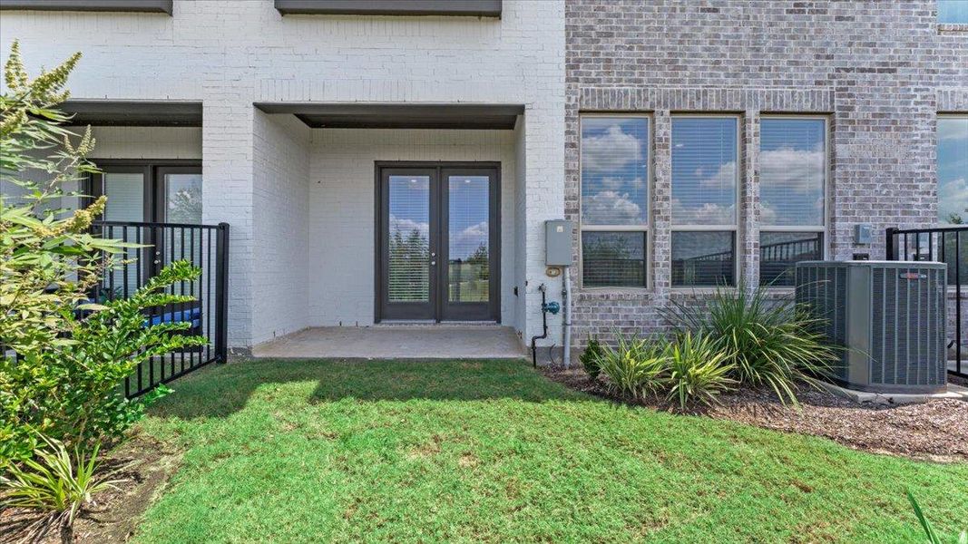 View of exterior entry with french doors, brick siding, a yard, and a patio View of exterior entry with french doors, brick siding, a yard, and a patio