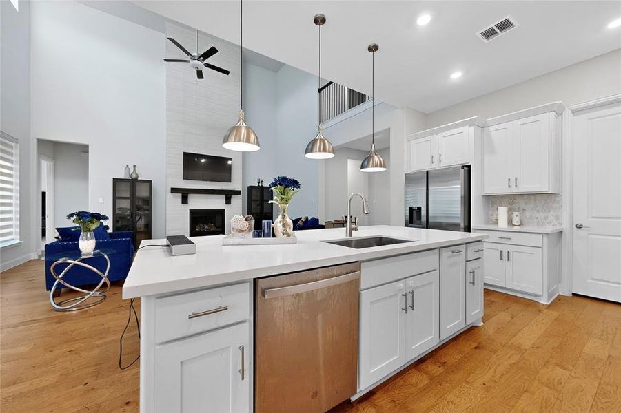 Kitchen featuring white cabinets, stainless steel appliances, a large fireplace, open floor plan, and a breakfast bar area