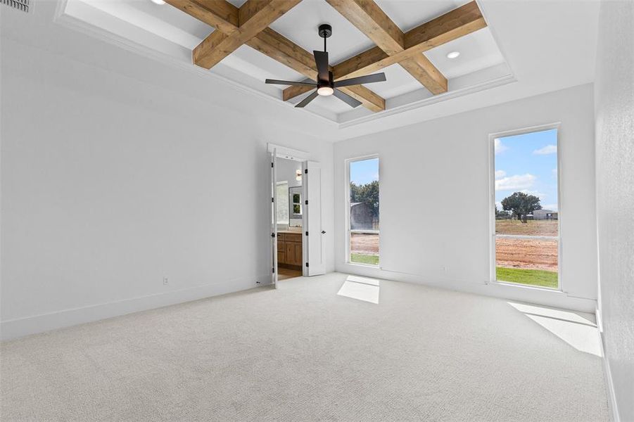 Carpeted empty room featuring coffered ceiling, beam ceiling, and ceiling fan
