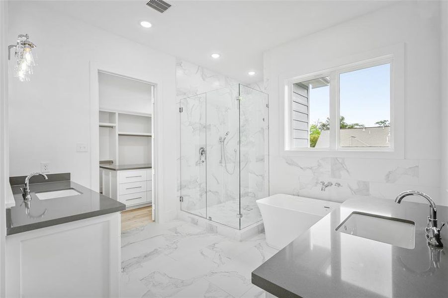 The primary bath features custom cabinetry, dual vanities, large soaking tub and stunning porcelain flooring.