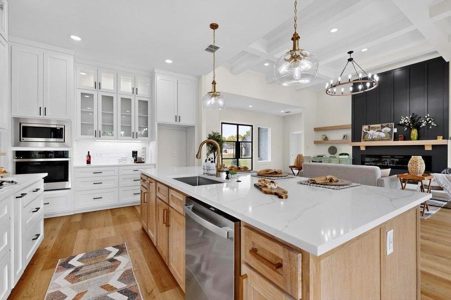 Kitchen featuring light wood-style flooring, open floor plan, beam ceiling, glass insert cabinets, and white cabinetry Kitchen featuring light wood-style flooring, open floor plan, beam ceiling, glass insert cabinets, and white cabinetry