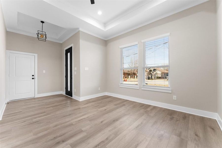 Foyer featuring ornamental molding, ceiling fan, light wood-type flooring, and a tray ceiling