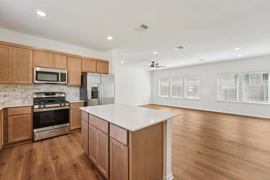A well-appointed kitchen features a central island, stainless steel appliances, and wood flooring, opening into a spacious living area. A well-appointed kitchen features a central island, stainless steel appliances, and wood flooring, opening into a spacious living area.