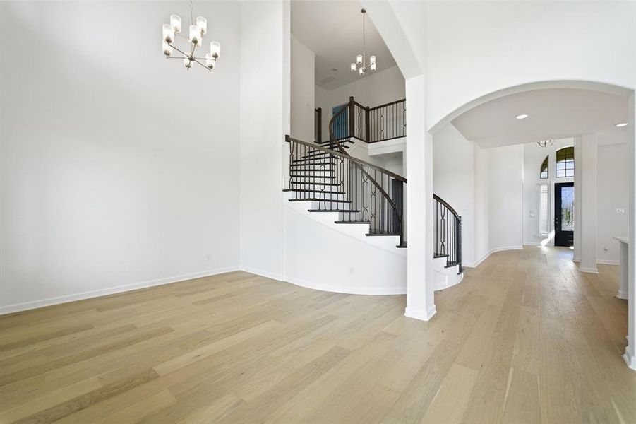 Grand foyer showcasing a curved staircase with wrought iron balusters and rich wood-finish handrails