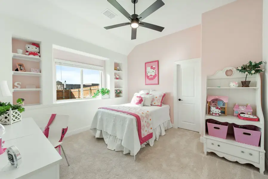 Child's bedroom with pink walls, built-in shelves, ceiling fan, and white furniture on carpet