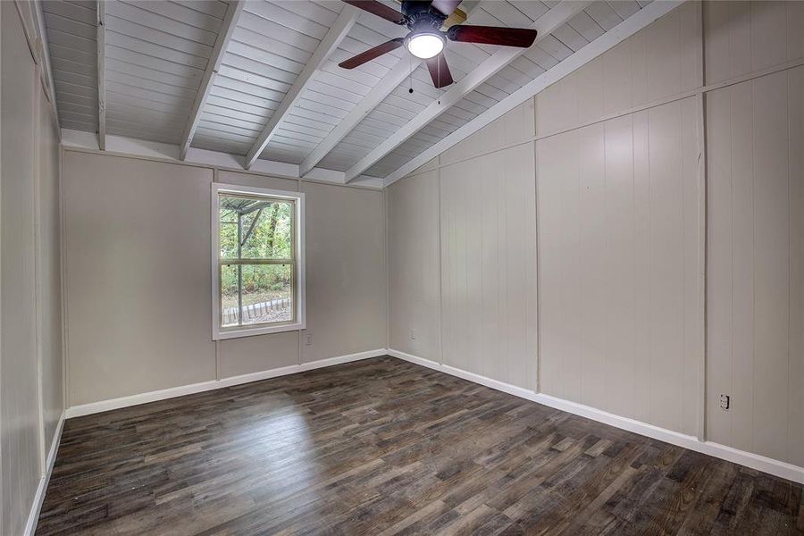 Empty room with dark wood-type flooring, ceiling fan, wood ceiling, and lofted ceiling with beams