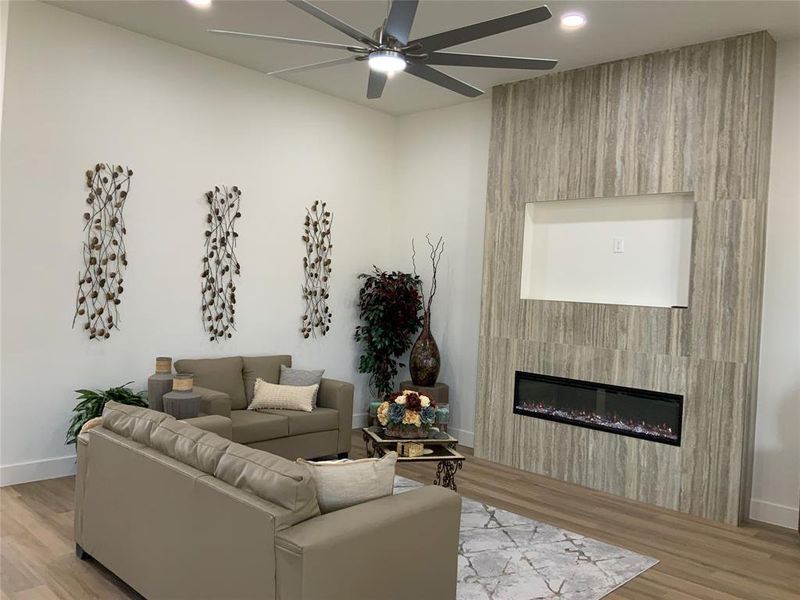 Living room featuring light wood-style flooring, a large fireplace, a ceiling fan, and recessed lighting Living room featuring light wood-style flooring, a large fireplace, a ceiling fan, and recessed lighting