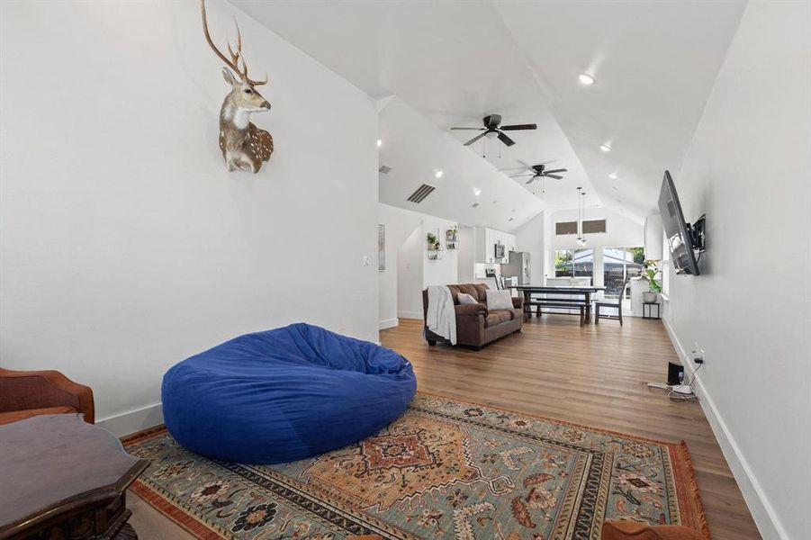 Living area with wood finished floors, high vaulted ceiling, a ceiling fan, and recessed lighting