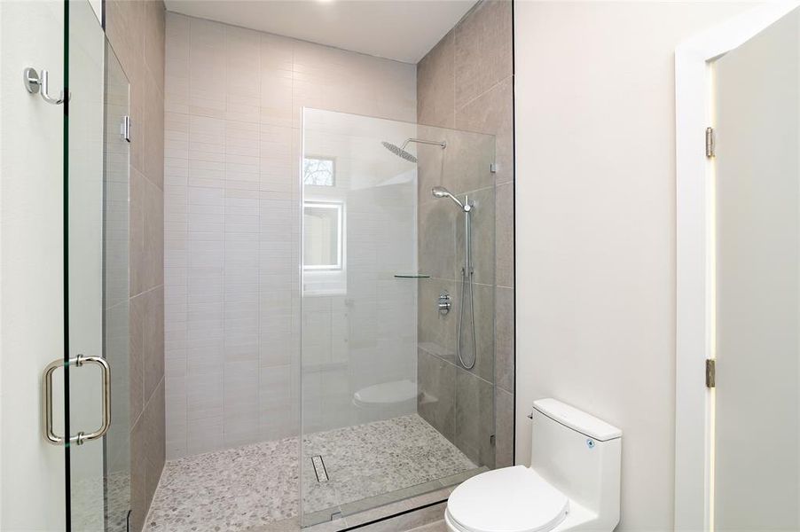 Bathroom with toilet and a shower with shower door