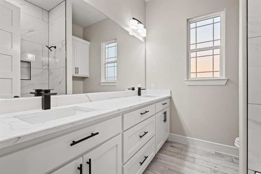 Full bathroom featuring double vanity, wood finish floors, and a marble finish shower