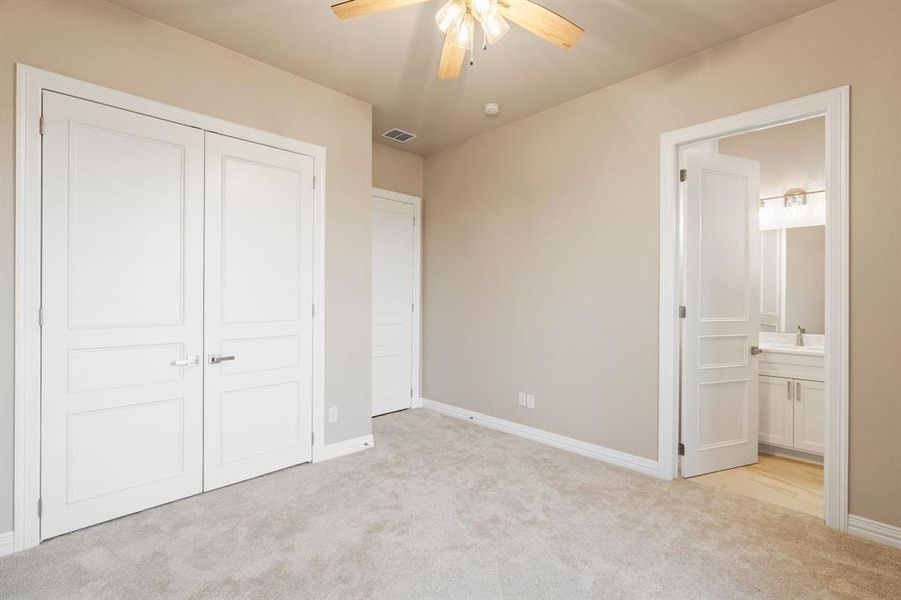 Unfurnished bedroom featuring light carpet, ensuite bath, a closet, and ceiling fan