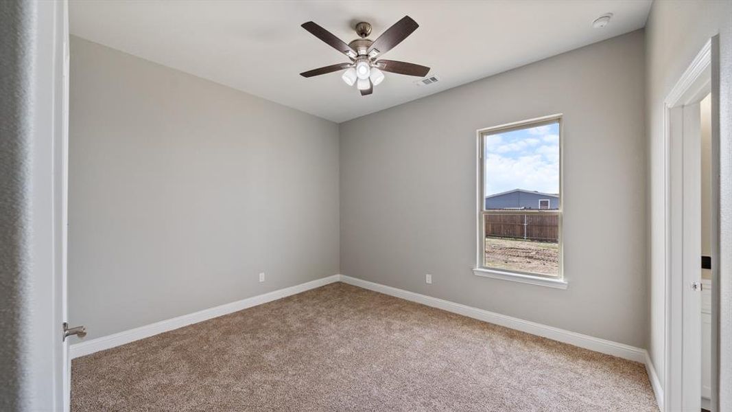 Unfurnished room with carpet floors, baseboards, visible vents, and a ceiling fan