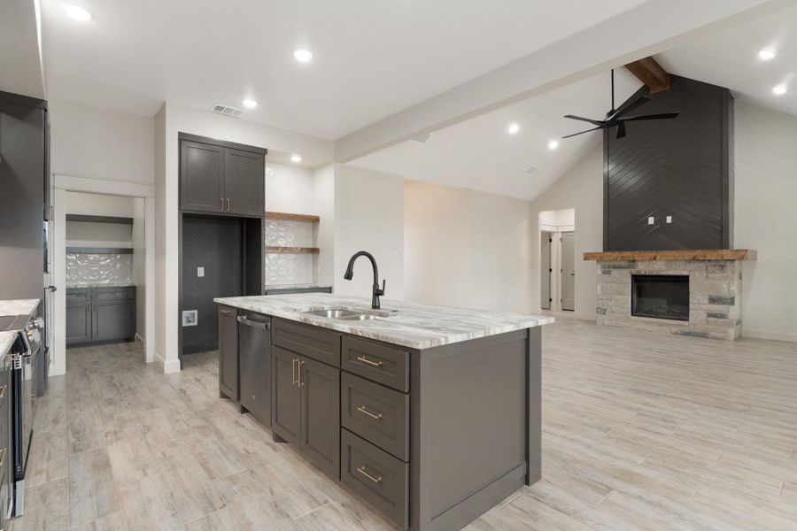 Kitchen with light stone counters, light wood-style flooring, a fireplace, appliances with stainless steel finishes, and open floor plan