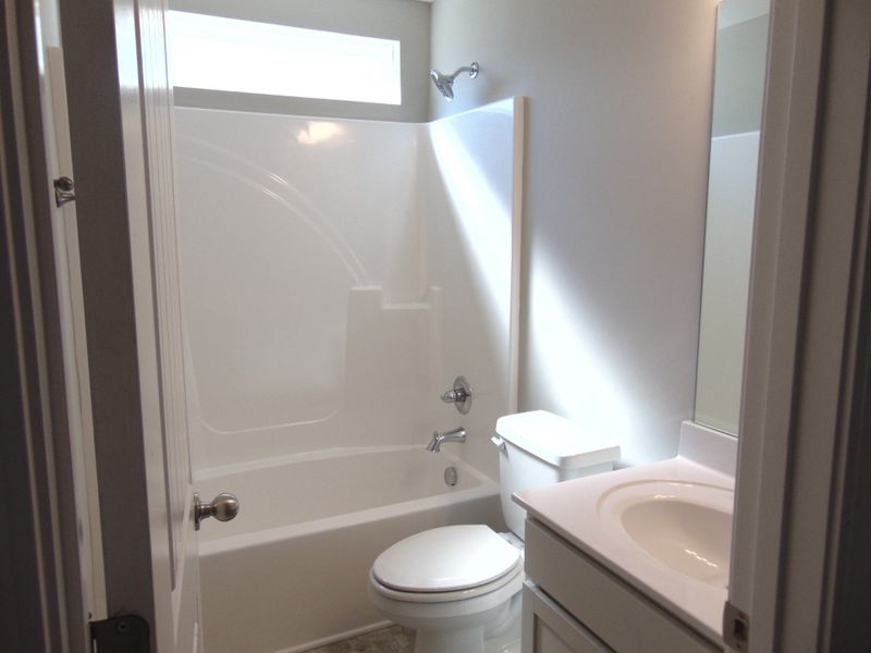 The second bathroom has a elongated toilet, a bath and shower combo, and a modern sink. There is also a linen closet for extra space.