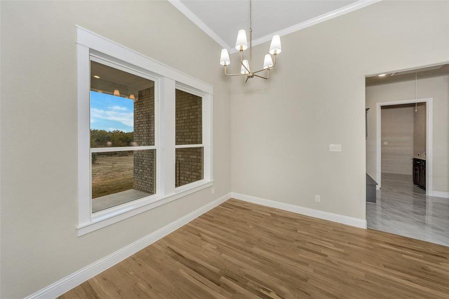 Unfurnished room with wood-type flooring, crown molding, and a chandelier