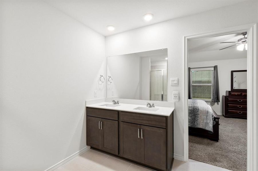 Ensuite bathroom with light tile patterned floors, double vanity, light colored carpet, a stall shower, and a ceiling fan