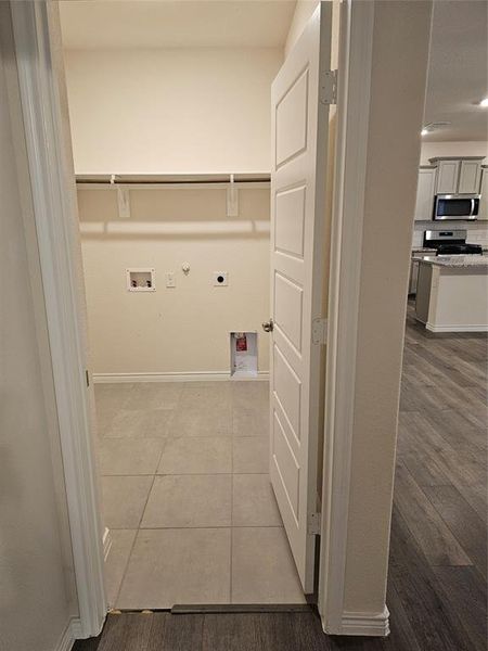 Washroom featuring gas dryer hookup, hookup for an electric dryer, washer hookup, and light tile patterned floors