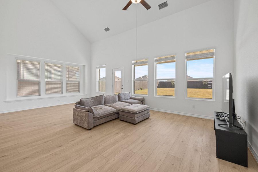 Living area featuring high vaulted ceiling, light wood-type flooring, and a ceiling fan