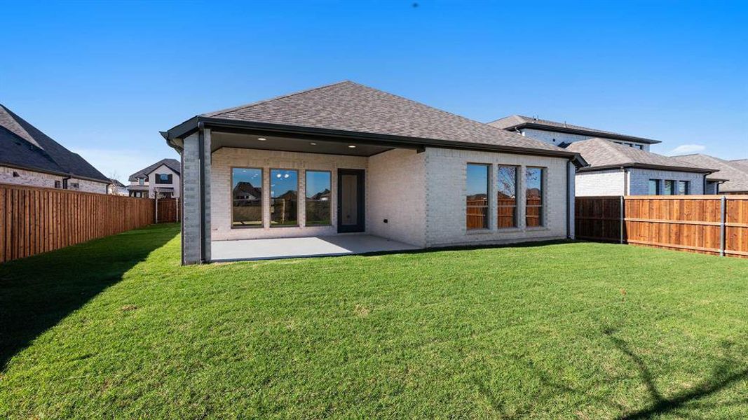 Back of property with a lawn and a patio