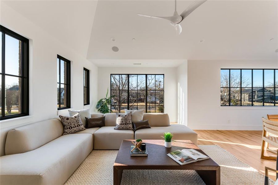 Living room with ceiling fan, wood-type flooring, and a healthy amount of sunlight