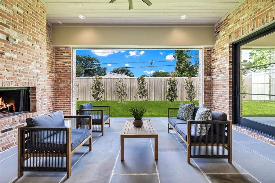 View of patio featuring ceiling fan and an outdoor living space with a fireplace