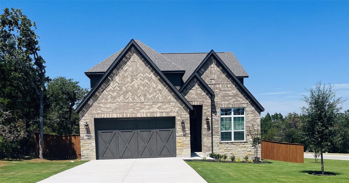 The Welch plan at The Colony is a beautiful two-story home with a long driveway, gorgeous cedar garage door, and lush front yard landscaping. The Welch plan at The Colony is a beautiful two-story home with a long driveway, gorgeous cedar garage door, and lush front yard landscaping.