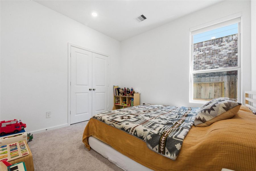 This bedroom features a cozy layout. It includes a window for natural light, a small bookshelf, and a closet with double doors. Perfect for a child's room or guest space.