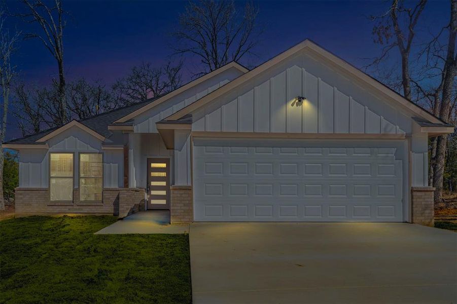 View of front of house with driveway, brick siding, and board and batten siding