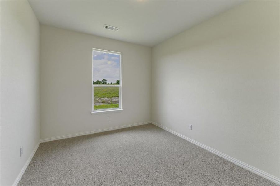 Bright room with light grey carpeting, white baseboards, and a single window offering a green landscape Bright room with light grey carpeting, white baseboards, and a single window offering a green landscape