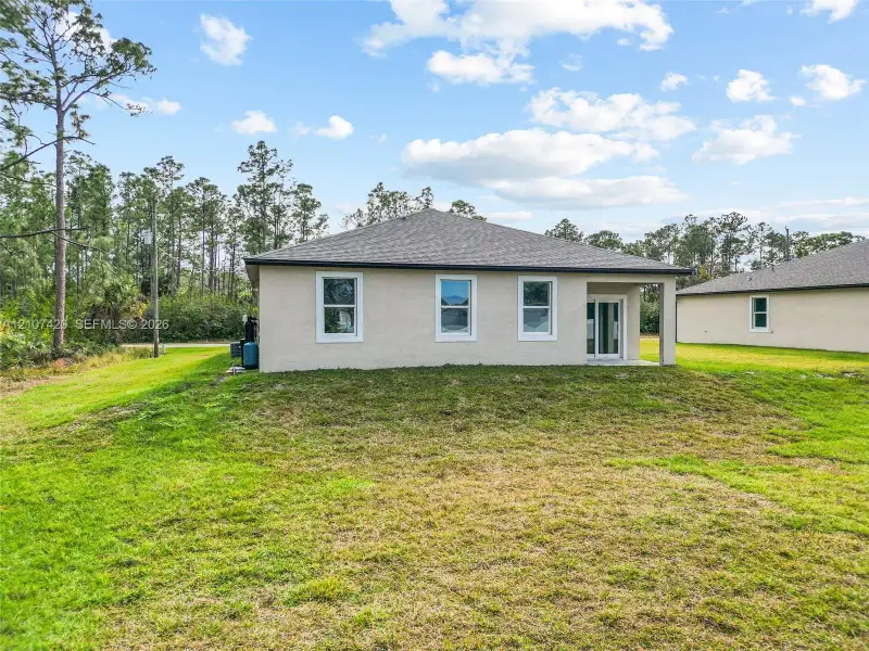 Stucco exterior, hipped roof, glass sliding door, and expansive rear lawn Stucco exterior, hipped roof, glass sliding door, and expansive rear lawn