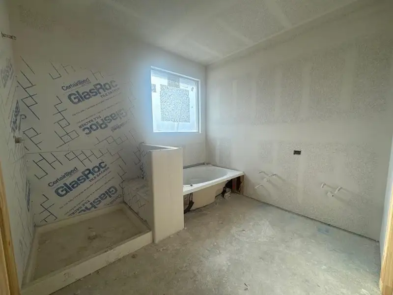 Bathroom under construction featuring a built-in shower pan, a partial shower wall, and a separate bathtub Bathroom under construction featuring a built-in shower pan, a partial shower wall, and a separate bathtub