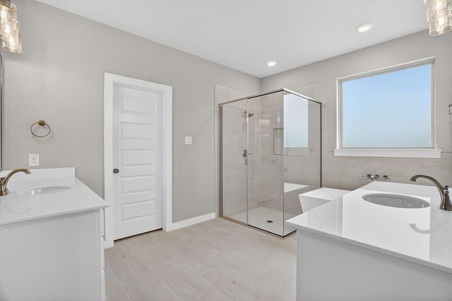 Bathroom featuring dual vanities with white countertops, a frameless glass shower enclosure, a built-in bathtub, and light tile flooring Bathroom featuring dual vanities with white countertops, a frameless glass shower enclosure, a built-in bathtub, and light tile flooring