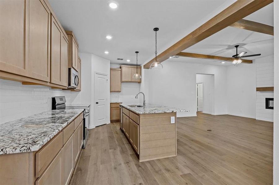 Kitchen with light hardwood / wood-style flooring, sink, an island with sink, beam ceiling, and appliances with stainless steel finishes