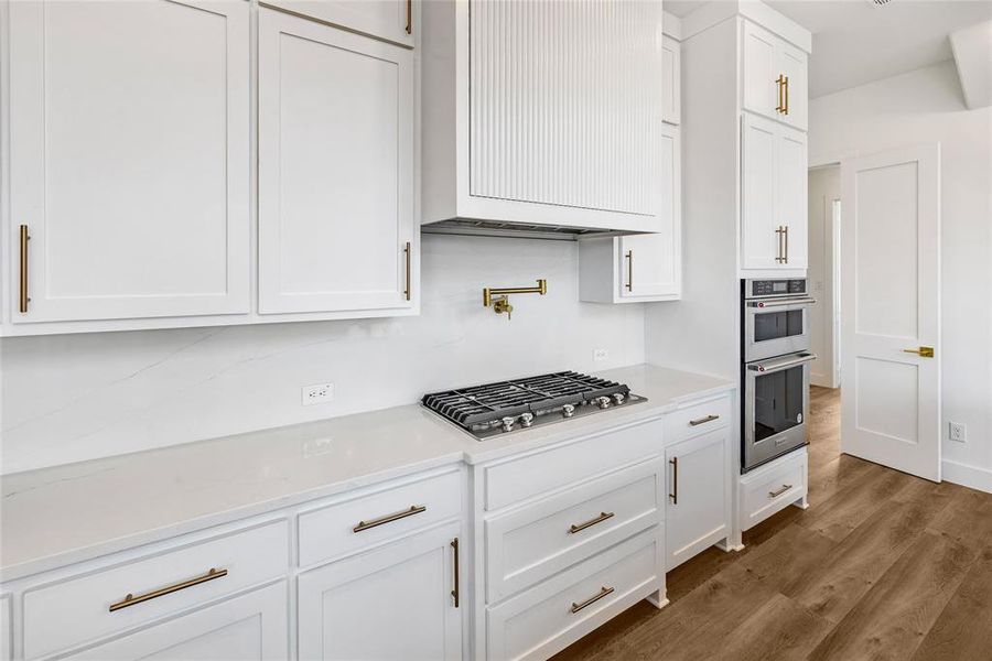 Kitchen with stainless steel appliances, wall chimney exhaust hood, dark hardwood / wood-style floors, and white cabinets