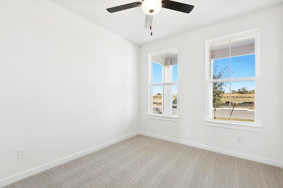 Carpeted spare room with baseboards and ceiling fan