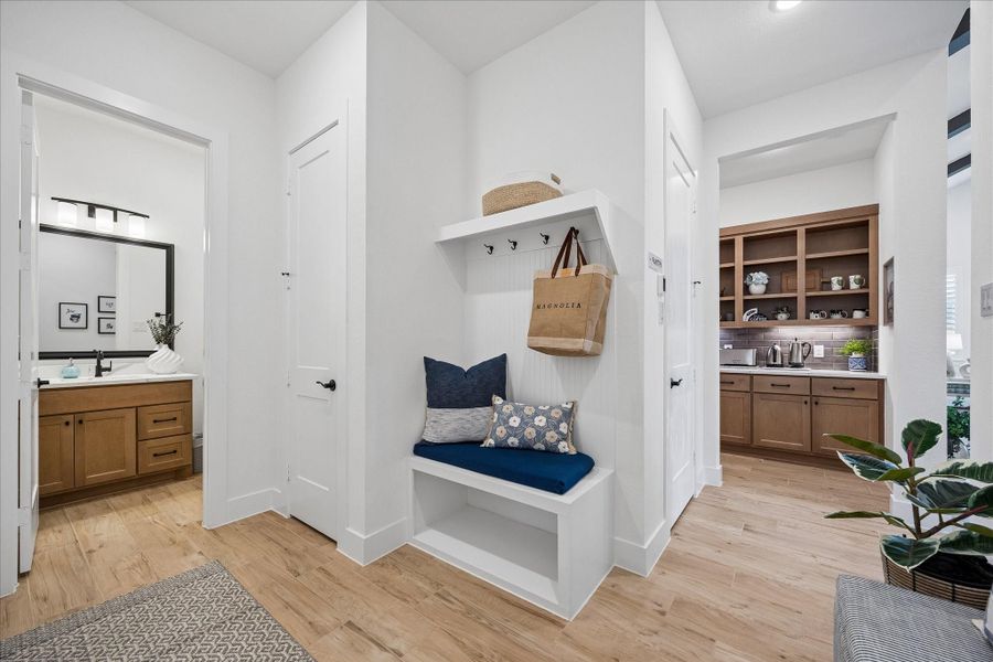 As you enter from the garage, you are greeted by a functional mudroom featuring a built-in bench with storage cubbies, closet, and convenient hanging hooks. This area also provides easy access to laundry room, powder room, a spacious walk-in pantry, and an extended pantry/coffee bar.