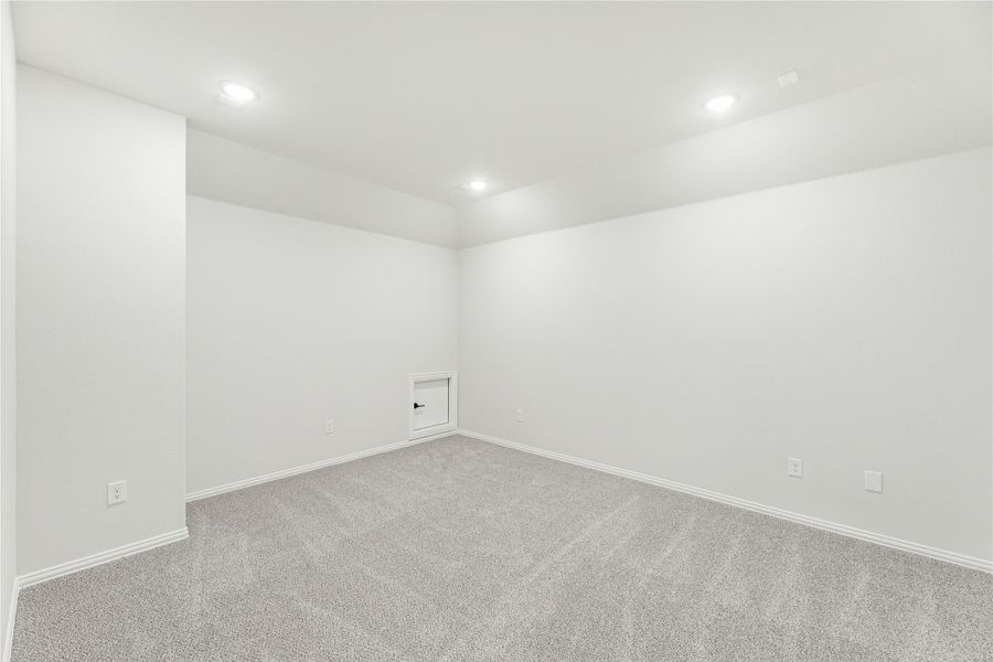 Empty room with gray carpet, white walls, recessed lighting, and a small access panel on the wall
