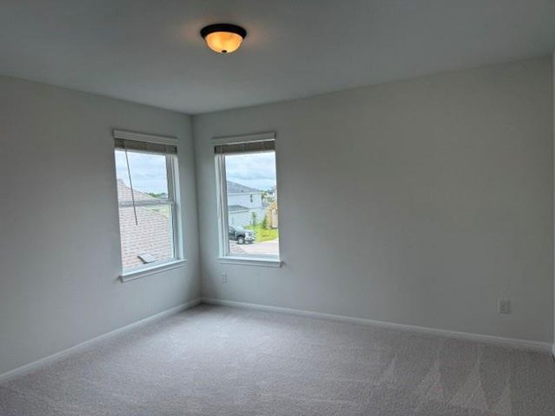 Neutral tone wall paint, light gray carpeting, and two windows with blinds