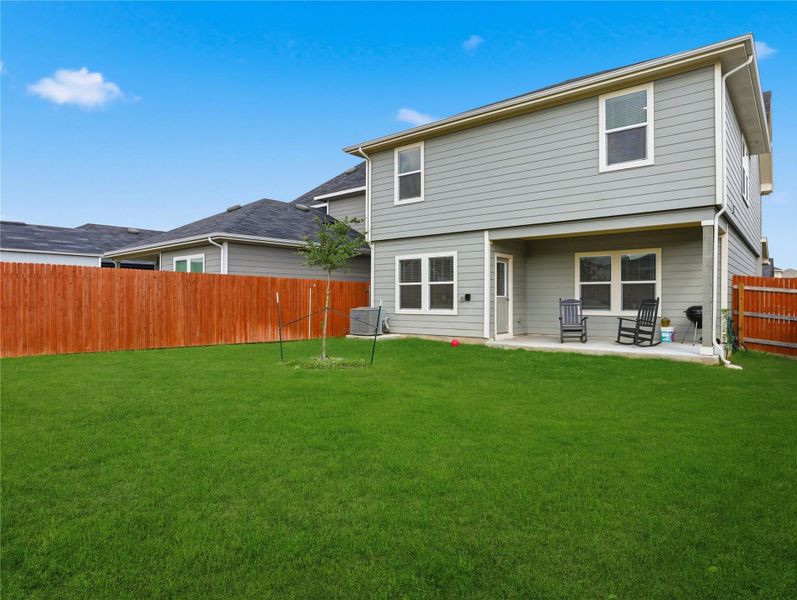 A spacious backyard features a covered patio and a fully fenced grassy lawn. A spacious backyard features a covered patio and a fully fenced grassy lawn.