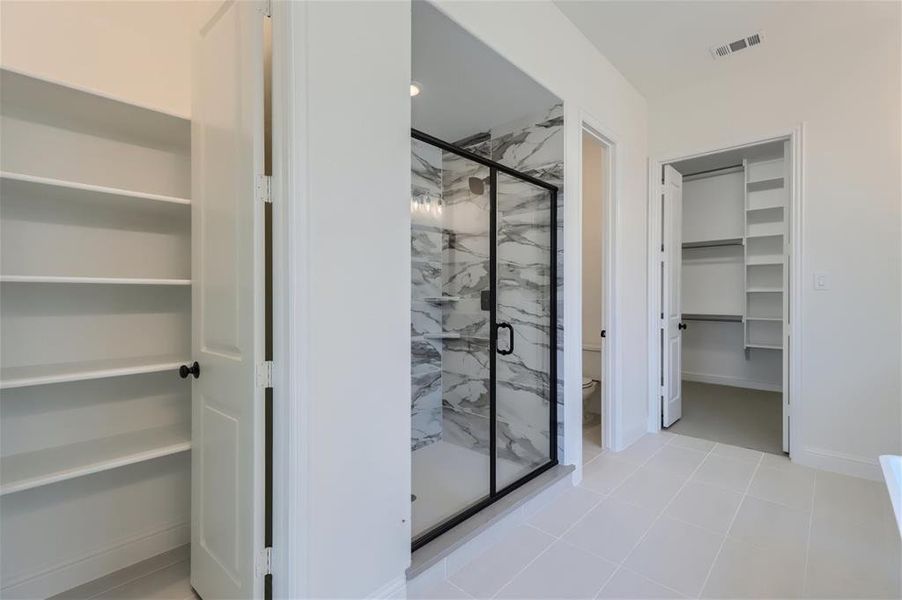 Bathroom featuring tile floors, a shower with door, and toilet