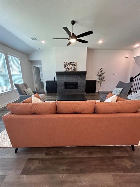 Living room featuring wood finished floors, vaulted ceiling, stairway, recessed lighting, and a fireplace Living room featuring wood finished floors, vaulted ceiling, stairway, recessed lighting, and a fireplace