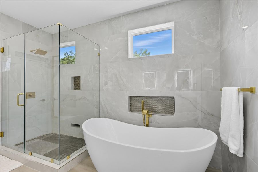 Full bathroom featuring tile walls, a soaking tub, and a marble finish shower