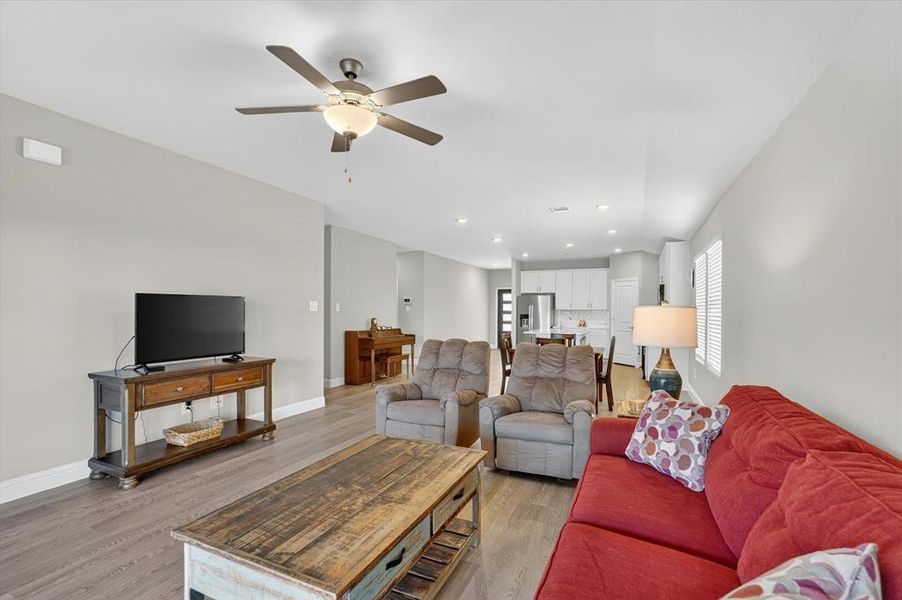 Open-concept living area featuring wood-finish flooring, recessed lighting, and a ceiling fan with integrated lighting Open-concept living area featuring wood-finish flooring, recessed lighting, and a ceiling fan with integrated lighting