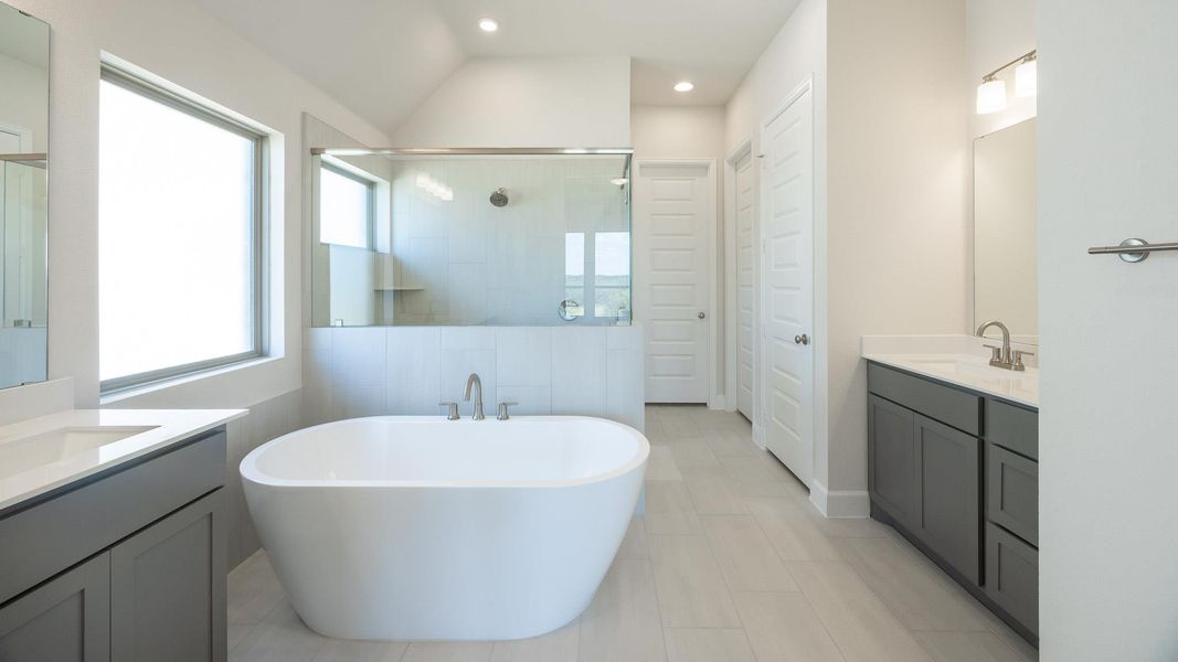 Full bathroom featuring a shower stall, a soaking tub, two vanities, recessed lighting, and a closet Full bathroom featuring a shower stall, a soaking tub, two vanities, recessed lighting, and a closet