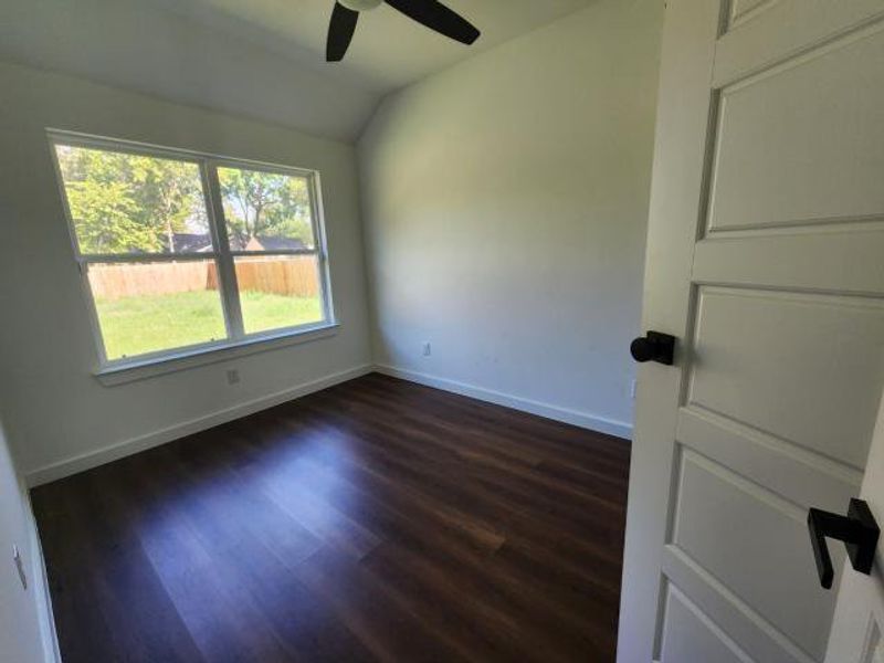 Empty room with lofted ceiling, dark wood-type flooring, and ceiling fan Empty room with lofted ceiling, dark wood-type flooring, and ceiling fan