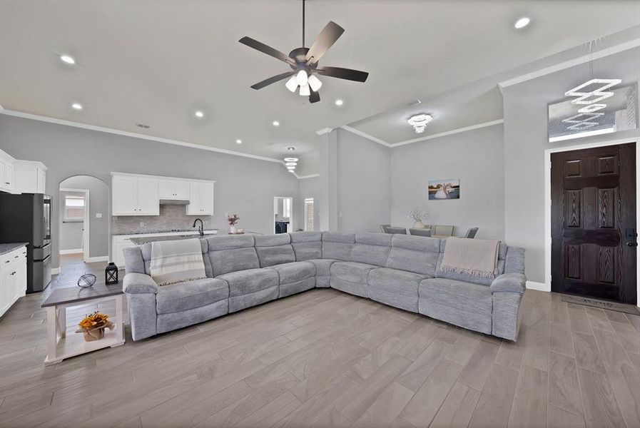 Living area with ceiling fan, arched walkways, ornamental molding, lofted ceiling, and baseboards Living area with ceiling fan, arched walkways, ornamental molding, lofted ceiling, and baseboards